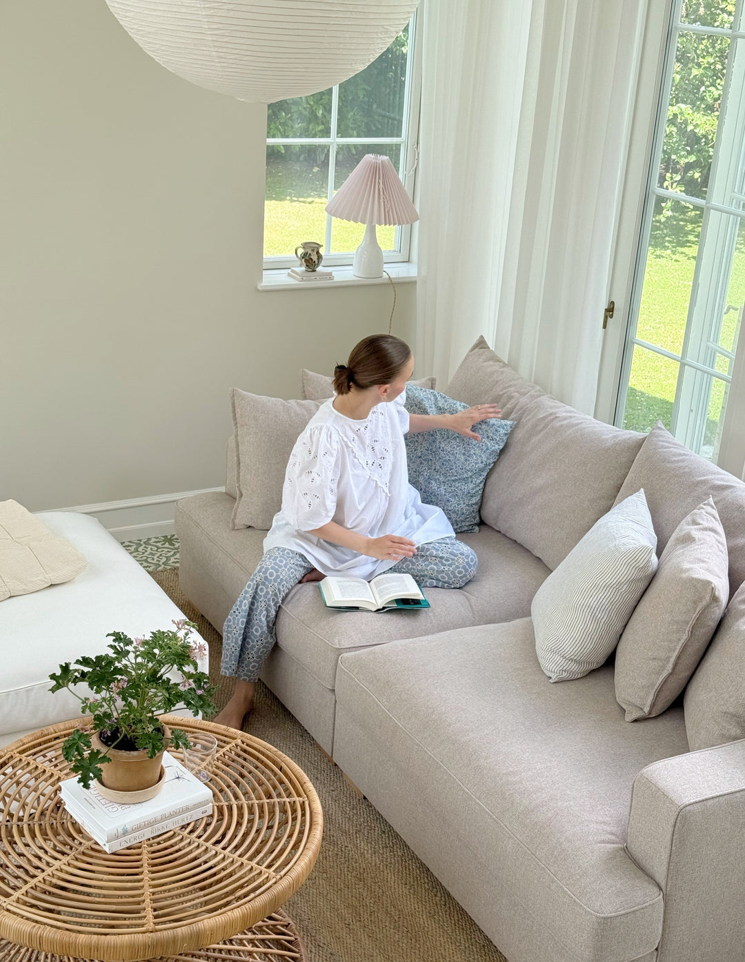 Cloud sofa i grå farve med chaiselong, produceret i Europa, placeret i stilfuldt rum med dekorative elementer.