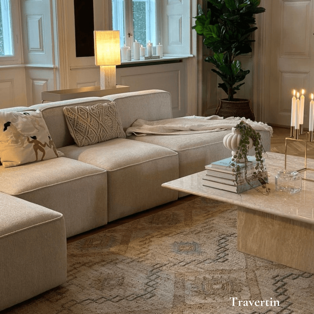 Elegant travertin sofabord i stue med moderne sofa, planter og dekorative detaljer. Produceret i Europa.